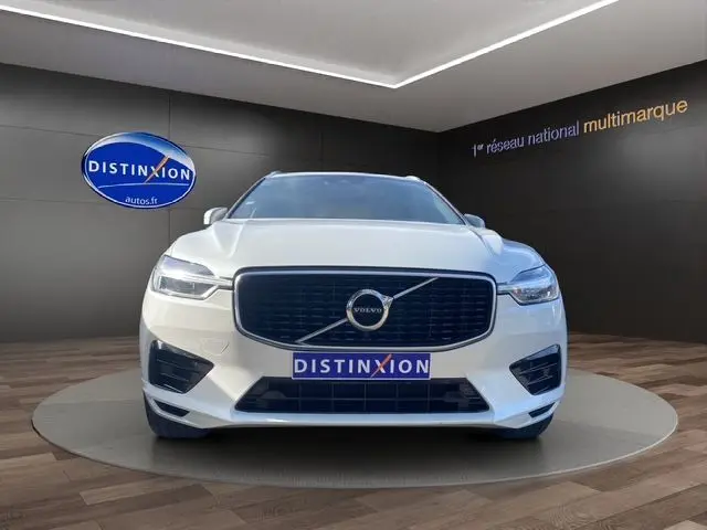 Vue frontale d'un Volvo XC60 blanc 2019 en finition R-DESIGN, avec calandre noire et logo distinctif au centre.
