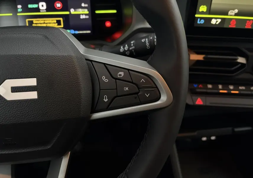 Gros plan sur le volant noir avec commandes multifonctions et tableau de bord digital du Dacia Duster 2026.
