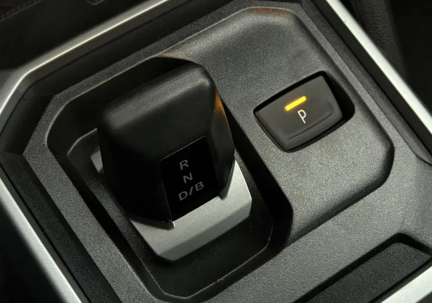 Gros plan sur la commande de boîte automatique et le bouton de frein de stationnement électrique du Dacia Duster blanc Glacier.