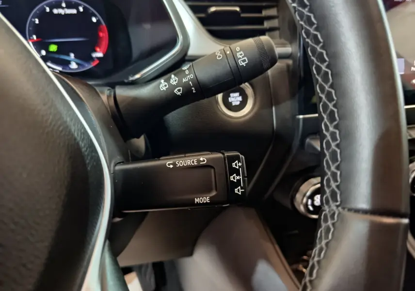 Gros plan sur la commande multifonction noire à gauche du volant du Renault Captur rouge 2024, bouton démarrage visible.