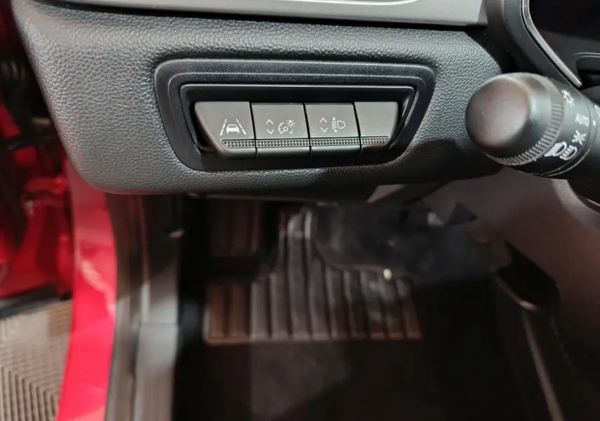 Boutons de réglage des aides à la conduite et phares sur le tableau de bord côté gauche d'un Renault Captur rouge 2024.