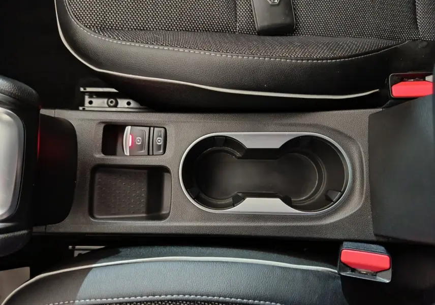 Vue plongeante sur la console centrale noire du Renault Captur rouge 2024, avec porte-gobelets et bouton frein électrique.