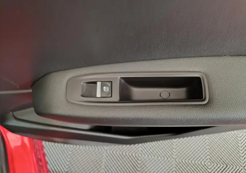 Commande de lève-vitre sur la porte avant gauche rouge d’un Renault Captur techno TCe 90 2024.