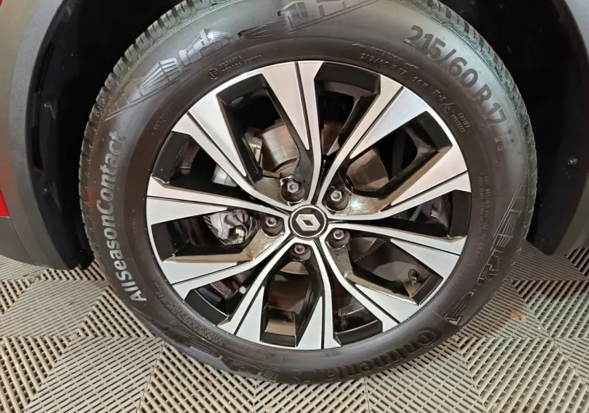 Gros plan sur la roue avant gauche du Renault Captur rouge 2024 avec jante alliage bicolore et logo central Renault.