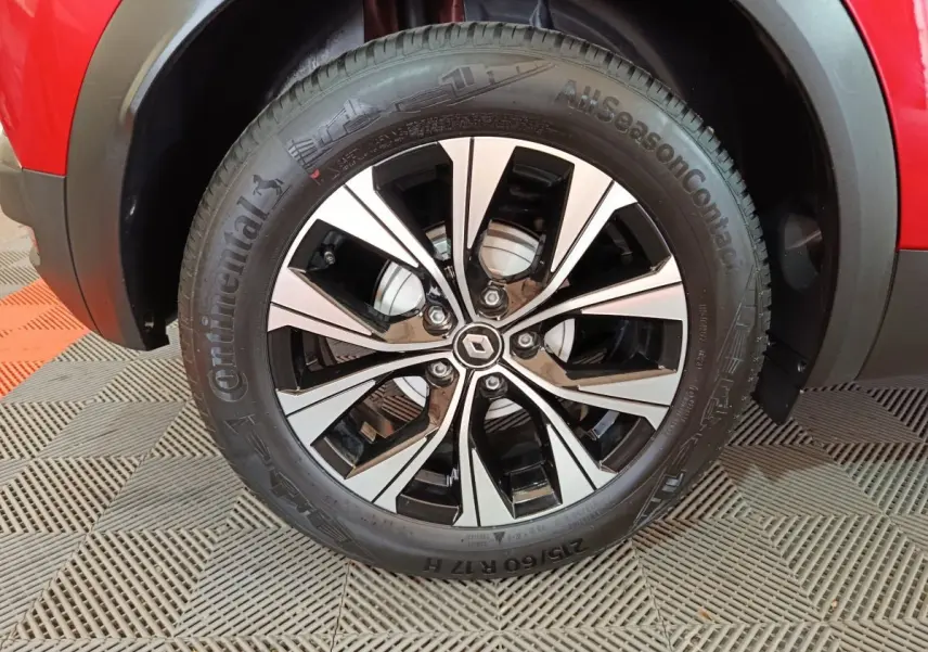 Gros plan sur la roue avant droite du Renault Captur rouge 2024, mettant en valeur la jante alliage bicolore et le pneu Continental.