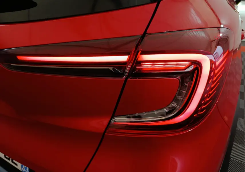 Gros plan sur le feu arrière droit rouge allumé du Renault Captur Techno TCe 90 2024 rouge brillant.