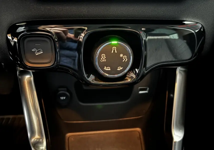 Gros plan sur la molette de sélection des modes de conduite et bouton de régulateur sur la console centrale noire du Citroën C3 Aircross gris clair.