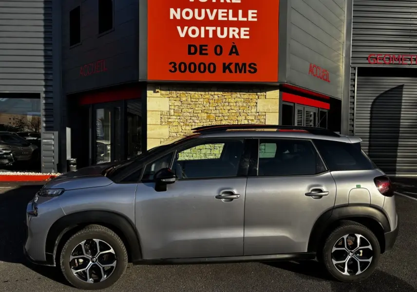 Profil côté gauche du Citroën C3 Aircross gris clair 2024, avec jantes alliage et toit noir contrasté visible.