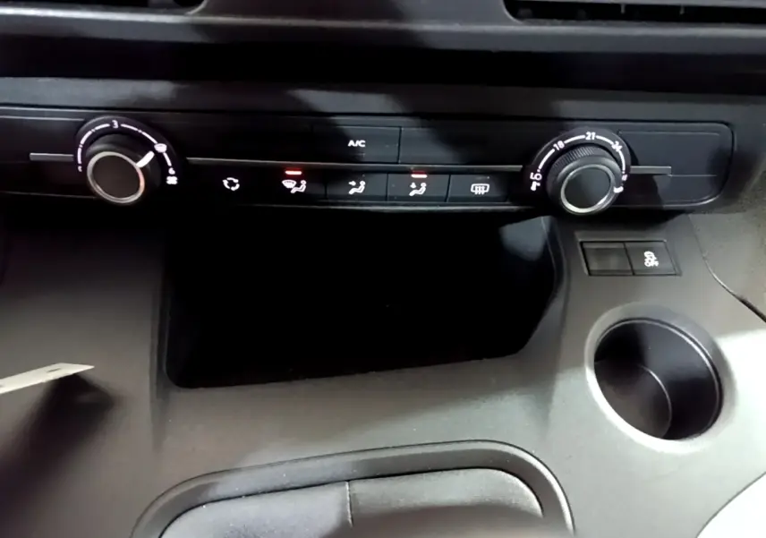 Détail de la console centrale du Citroën Berlingo XL blanc 2019, montrant les commandes de climatisation et un porte-gobelet.