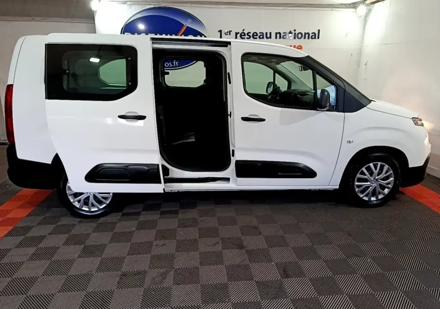Vue de profil droit d’un Citroën Berlingo blanc XL avec porte coulissante ouverte, intérieur sombre visible.