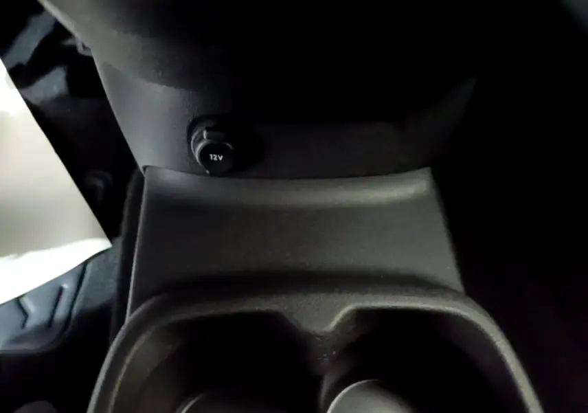 Prise 12V et porte-gobelets en plastique noir dans l'habitacle du Citroën Berlingo XL blanc, vue rapprochée intérieure.