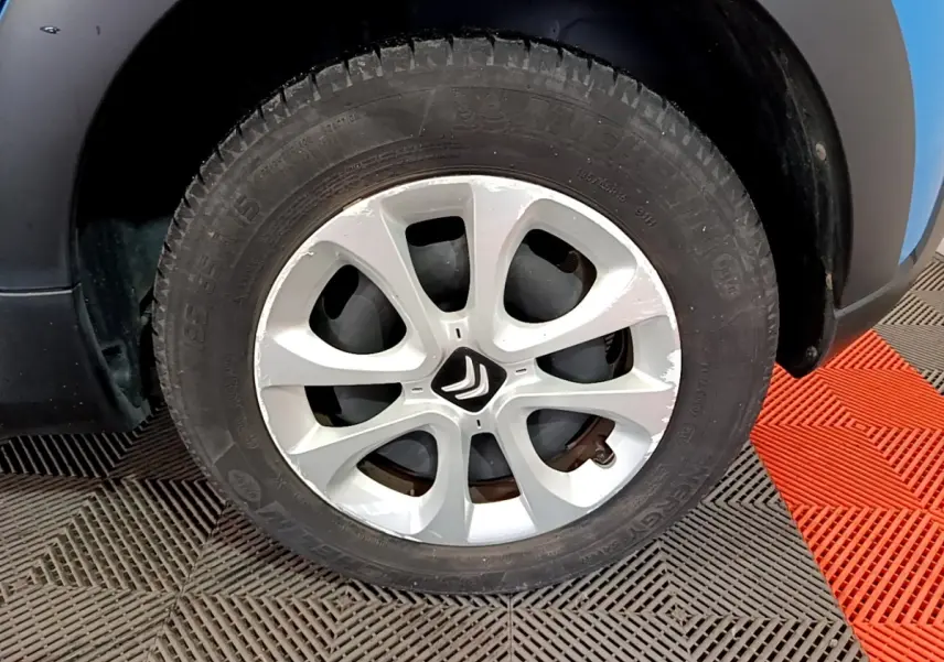 Gros plan sur la roue avant droite d’une Citroën C3 bleu, jante alliage argentée avec logo Citroën central.
