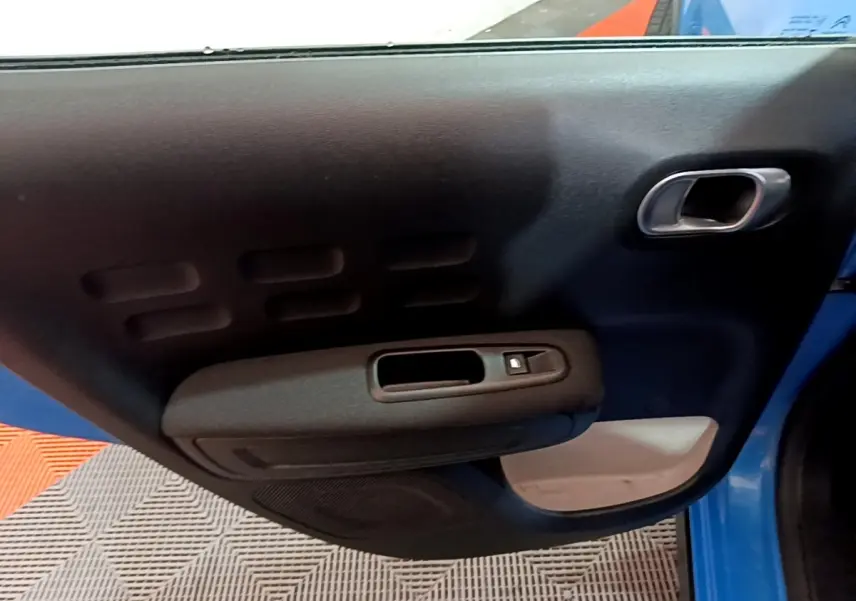 Vue intérieure de la porte avant gauche bleu de la Citroën C3 2017 avec poignée et commande de vitre électrique.