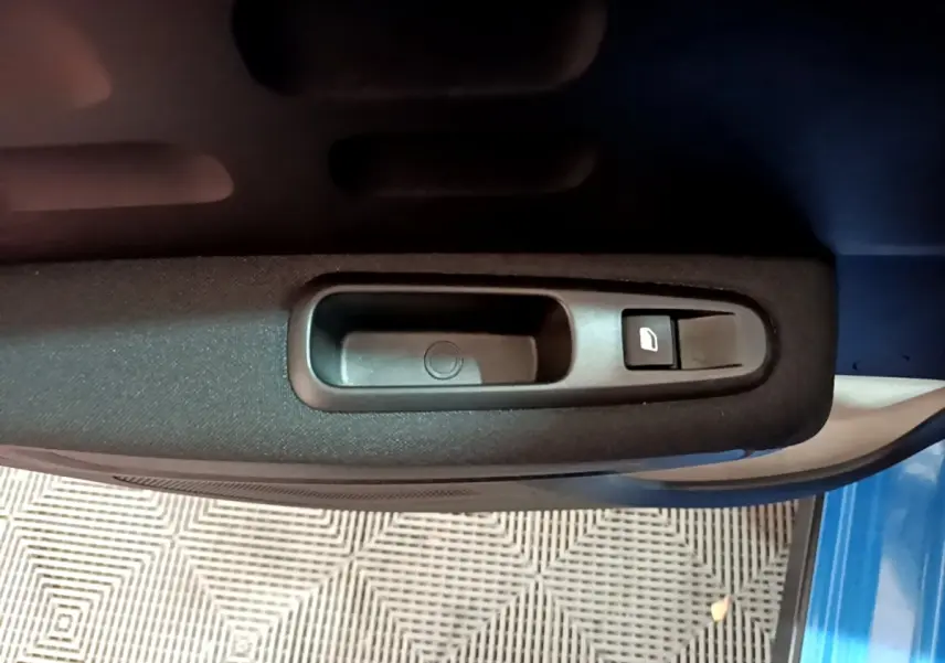 Gros plan sur la commande de lève-vitre côté conducteur d'une Citroën C3 bleue, intérieur tissu noir.