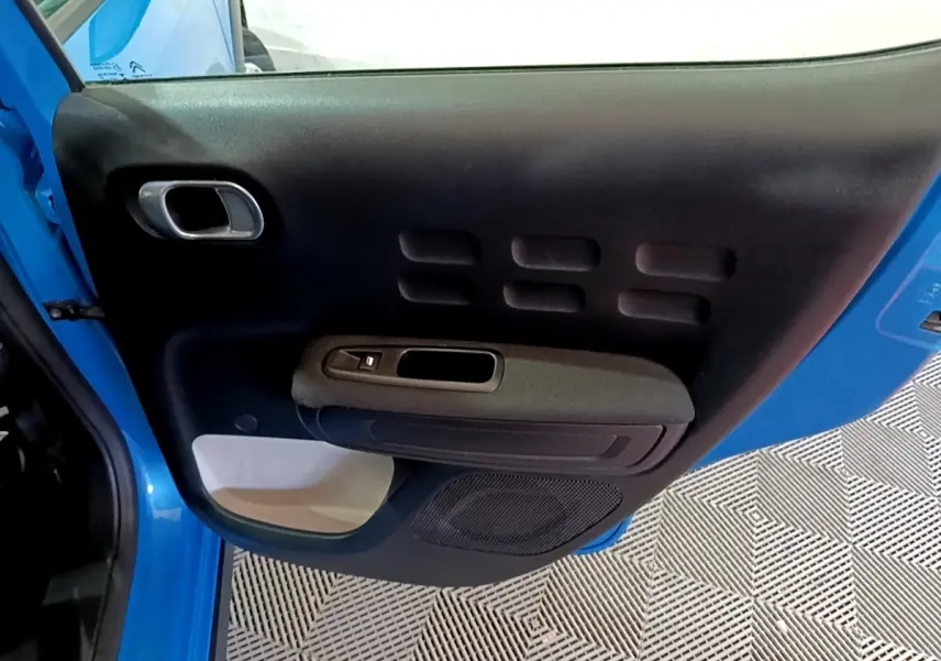 Vue intérieure de la porte avant gauche bleu de la Citroën C3 2017 avec poignée et commande de vitre électrique.
