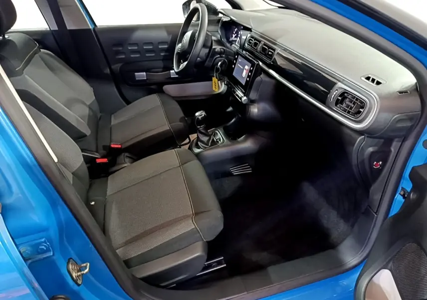 Vue intérieure côté conducteur d'une Citroën C3 bleu 2017, montrant sièges noirs et tableau de bord avec écran tactile.