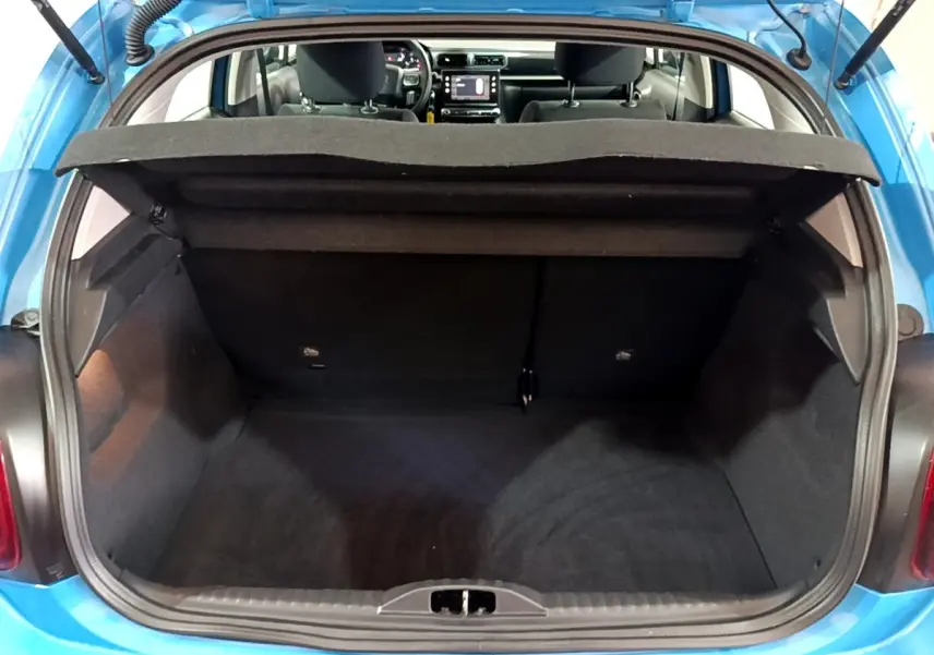Coffre ouvert d'une Citroën C3 bleu, vue arrière montrant l'intérieur spacieux et la tablette cache-bagages relevée.