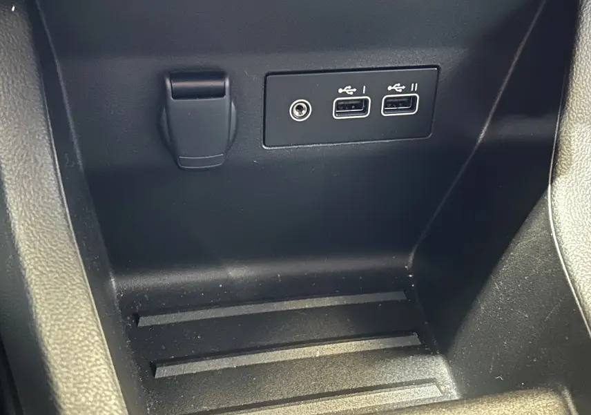 Gros plan sur la console centrale noire de la Renault Clio V, montrant deux ports USB et une prise jack.