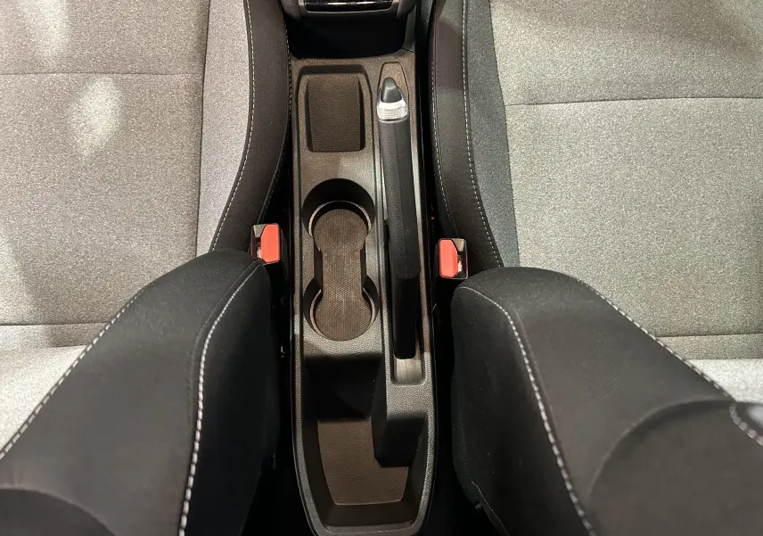 Vue plongeante sur la console centrale noire et les sièges tissu gris de la Renault Clio V Bluetci 100 Evolution.