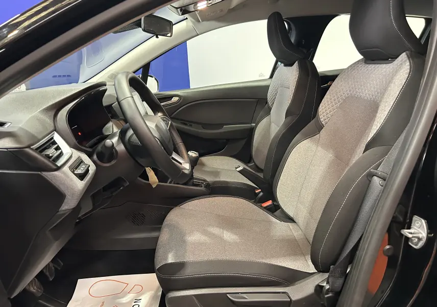 Vue intérieure côté conducteur de la Renault Clio V noire, mettant en valeur les sièges tissu et cuir gris et la console centrale.