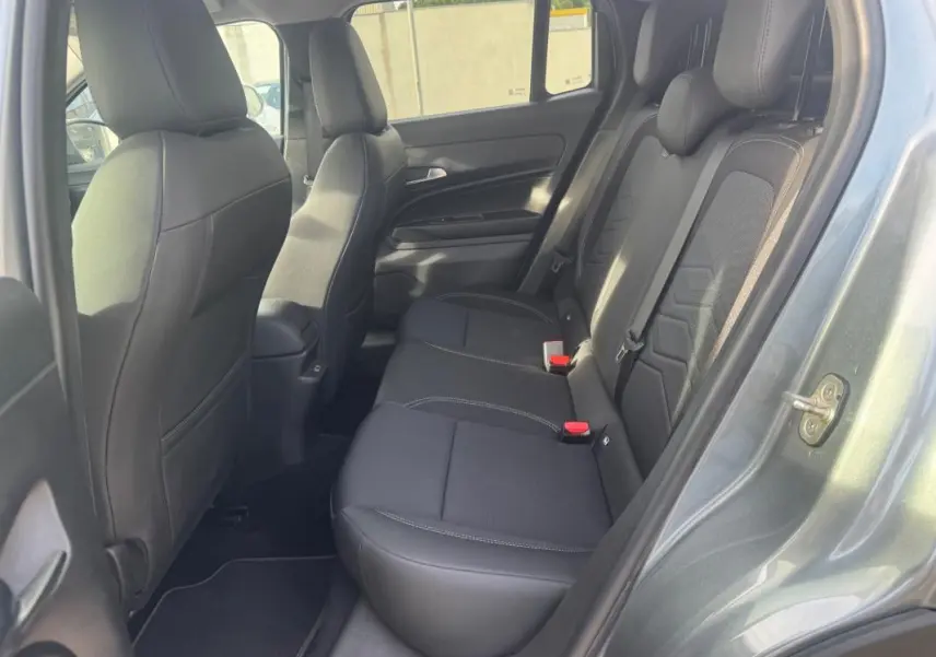 Vue intérieure côté droit montrant la banquette arrière noire du Jeep Avenger gris 2025 avec finitions tissu et cuir.