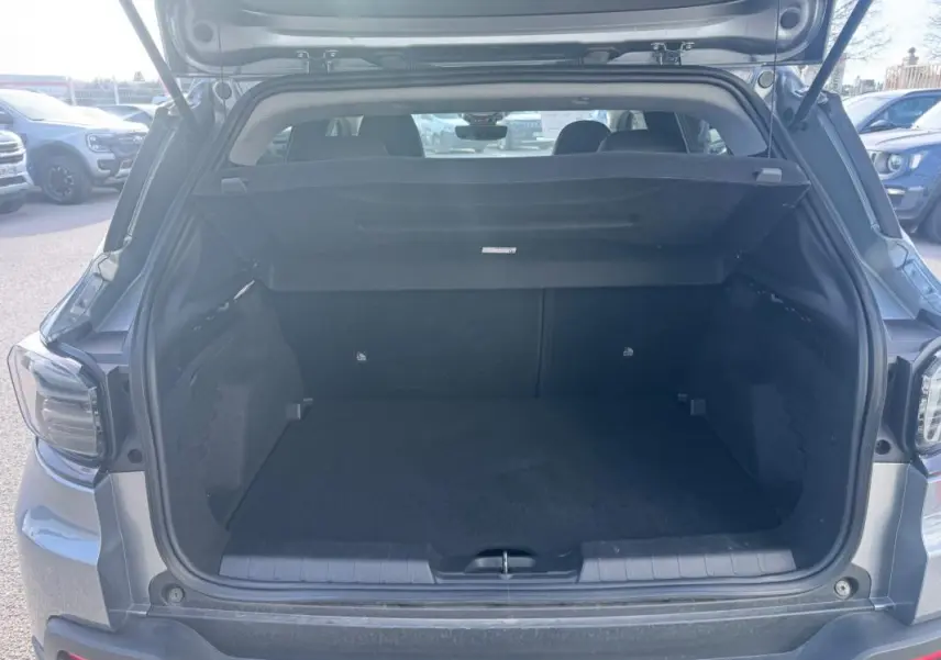 Coffre ouvert d’un Jeep Avenger gris 2025, vue arrière montrant l’espace de chargement vide et la plage arrière relevée.