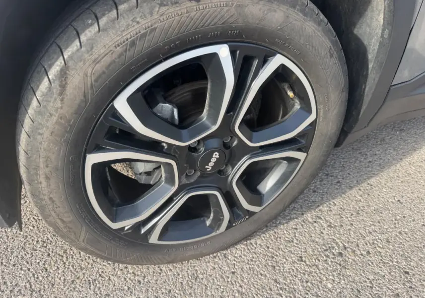 Gros plan sur la roue avant droite du Jeep Avenger gris 2025, jante alliage noire et argentée au design moderne.