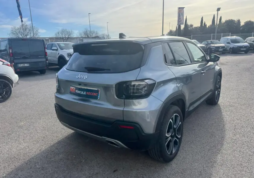 Jeep Avenger gris en 3/4 arrière droit, avec feux arrière sombres et jantes alliage distinctives.