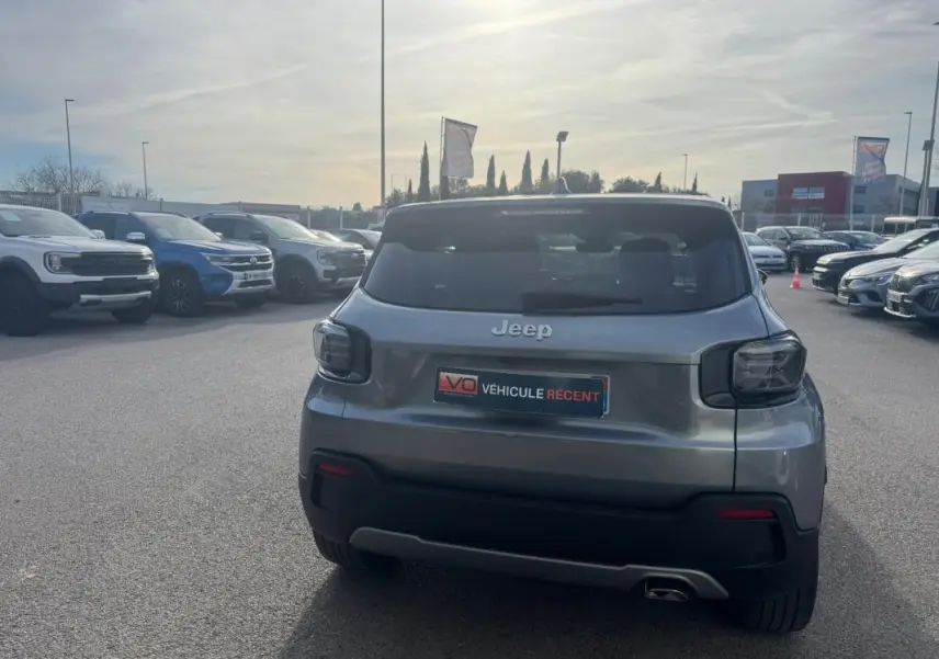 Vue arrière d'un Jeep Avenger gris 2025 garé en extérieur, avec feux arrière foncés et plaque "Véhicule récent".