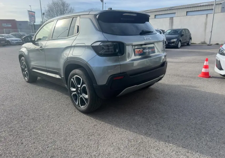 Jeep Avenger gris vue 3/4 arrière droit, avec jantes noires et détails noirs contrastants sur le pare-chocs.