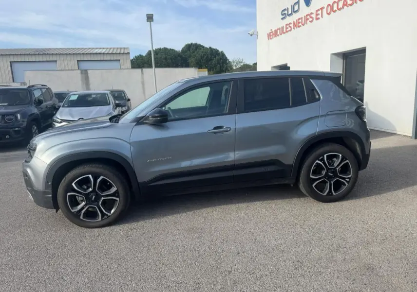 Vue de profil côté gauche d'un Jeep Avenger gris 2025 avec jantes noires et détails noirs contrastants.