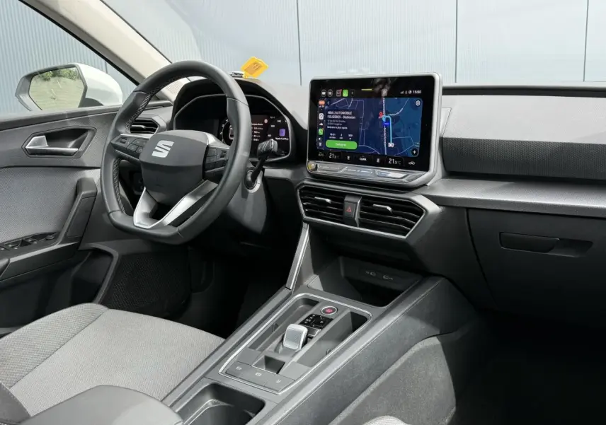 Vue intérieure côté conducteur du SEAT Leon 2025, tableau de bord noir avec écran tactile central et volant multifonction.