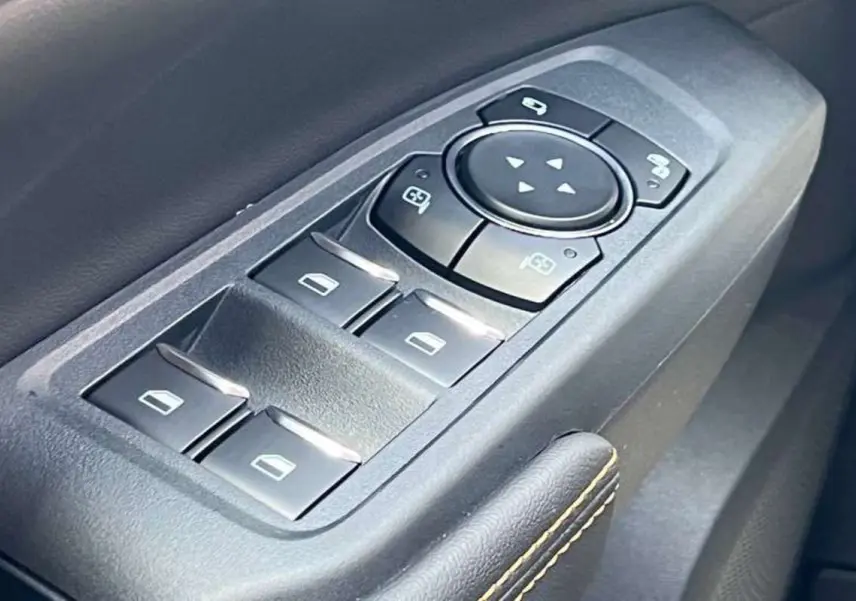 Gros plan sur les commandes des vitres électriques et rétroviseurs du côté gauche intérieur du Ford Ranger Wildtrak Plus noir agate.