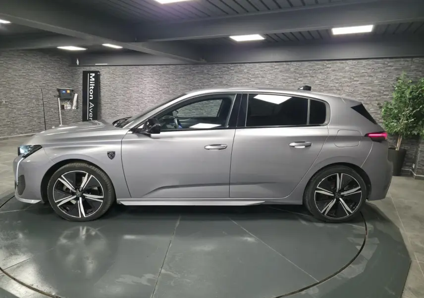 Peugeot 308 gris métallisé vue de profil côté gauche, avec jantes alliage noires et vitres surteintées.