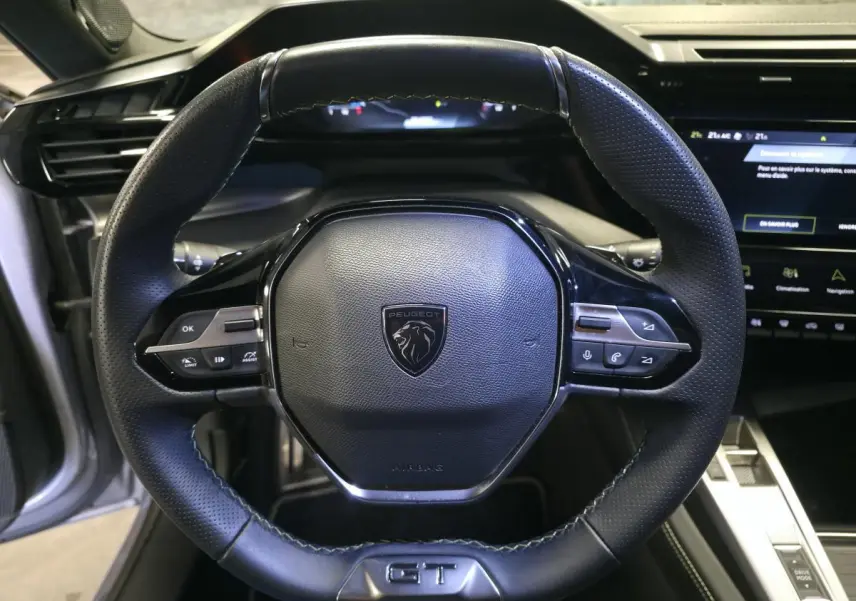 Vue rapprochée du volant cuir noir avec logo Peugeot et badge GT du Peugeot 308 1.6 PHEV 2024.
