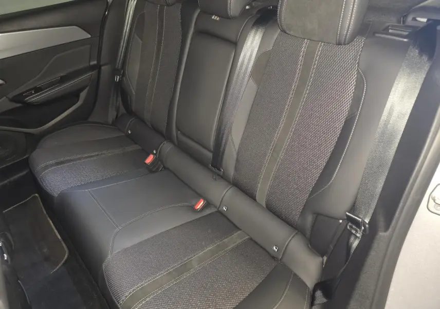 Vue intérieure côté gauche des sièges arrière noirs en tissu et cuir de la Peugeot 308 1.6 PHEV GT 2024.
