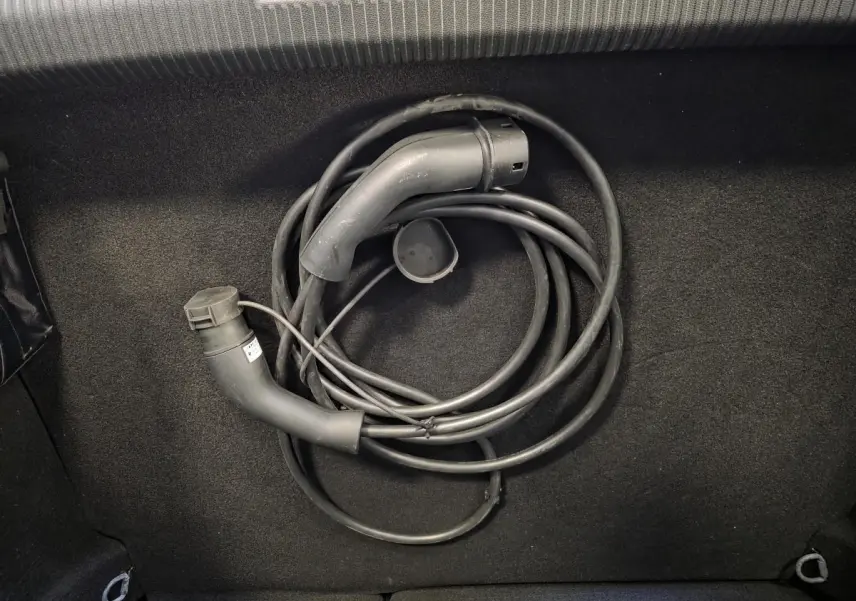 Gros plan sur câble de recharge noir enroulé dans le coffre d'une Peugeot 308 gris hybride rechargeable 2024.