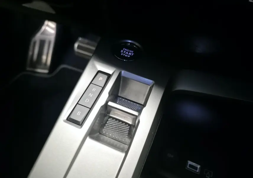 Gros plan sur la console centrale grise de la Peugeot 308 2024 avec sélecteur de boîte auto et bouton start/stop.