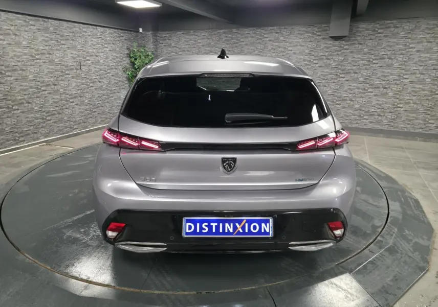 Vue arrière d'une Peugeot 308 gris métallisé 2024 avec feux arrière LED en forme de griffe et logo lion central.