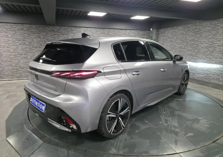 Vue 3/4 arrière droite de la Peugeot 308 GT hybride rechargeable gris métallisé avec feux arrière LED distinctifs.