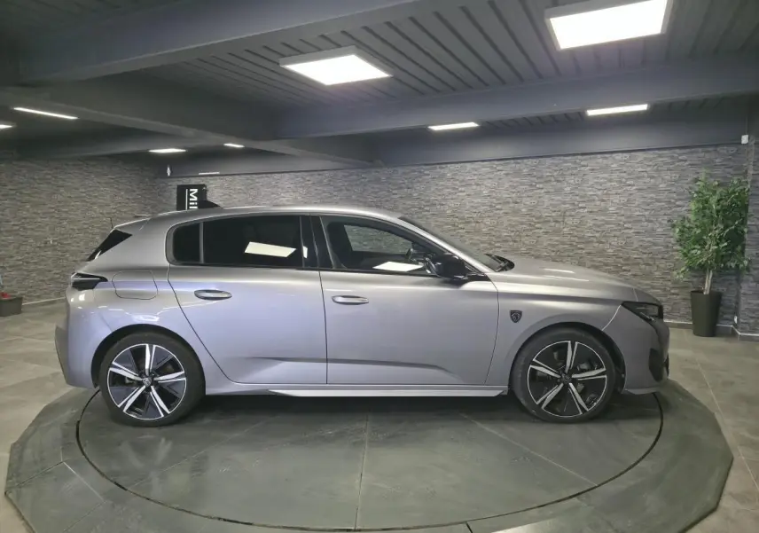 Peugeot 308 gris métallisé vue de profil côté gauche, avec jantes alliage noires et vitres surteintées.