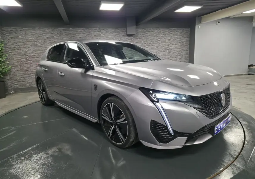 Peugeot 308 gris métallisé vue 3/4 avant droit avec calandre noire brillante et feux LED griffés.