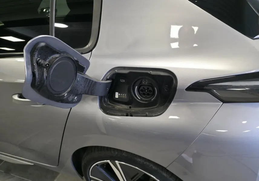 Prise de recharge ouverte côté gauche arrière d’une Peugeot 308 gris métallisé, avec jante alliage visible.