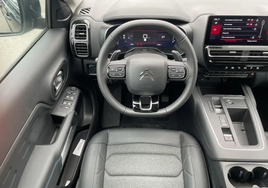 Vue intérieure de face du poste de conduite noir du Citroën C5 Aircross 2025 avec volant cuir multifonction et écran tactile.