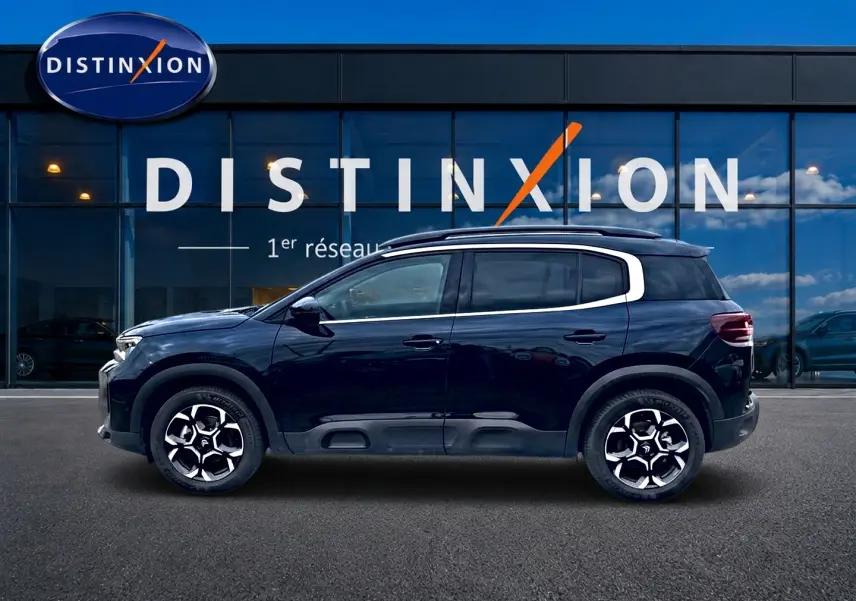 Profil droit du Citroën C5 Aircross noir 2025 avec jantes alu et barres de toit visibles devant une vitrine Distinxion.