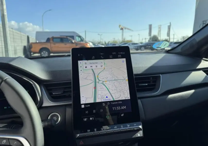 Vue intérieure du tableau de bord du Renault Captur gris Cassiopée, avec écran tactile central affichant la navigation.