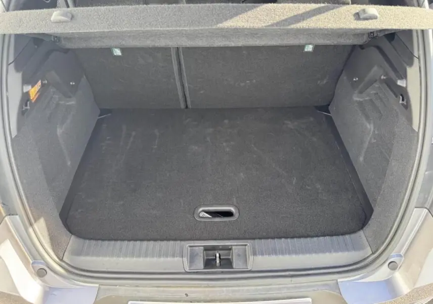Coffre ouvert vu de l'arrière du Renault Captur gris Cassiopée avec plancher de coffre mobile et intérieur noir.