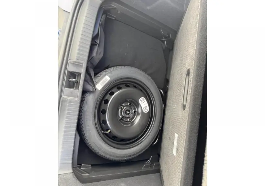 Vue plongeante sur la roue de secours noire dans le coffre du Renault Captur gris Cassiopée toit noir.