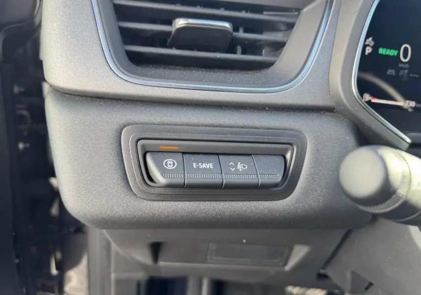 Gros plan sur les commandes situées à gauche du volant du Renault Captur II gris Cassiopée, avec bouton E-SAVE allumé.