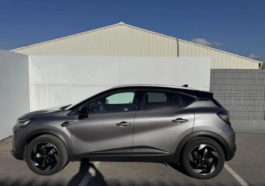 Profil droit du Renault Captur gris Cassiopée avec toit noir, jantes noires et lignes modernes visibles au soleil.